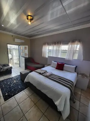 a bedroom with a large bed and a red couch at Tshedza Guest House in Pretoria