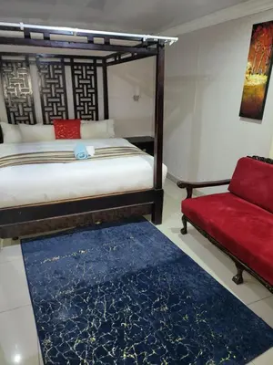 a bedroom with a bed and a red couch at Tshedza Guest House in Pretoria