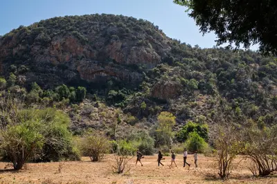 a group of people walking in front of a mountain at Hutwini Walking Camp by RETURN Africa in Makuleke Contract Park