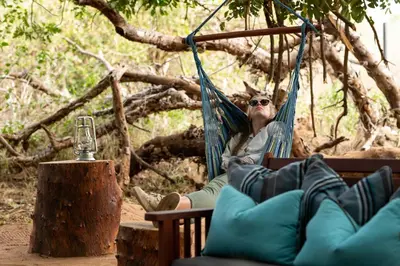 a woman sitting in a hammock in a tree at Hutwini Walking Camp by RETURN Africa in Makuleke Contract Park