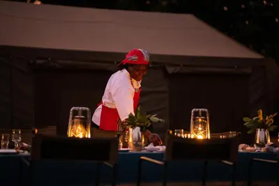 a woman standing in front of a table with lights at Hutwini Walking Camp by RETURN Africa in Makuleke Contract Park
