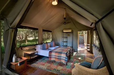 a bedroom in a tent with a bed and chairs at Hutwini Walking Camp by RETURN Africa in Makuleke Contract Park