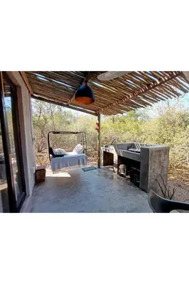 a covered patio with a bed and a table at The Nest - Marloth Park in Marloth Park