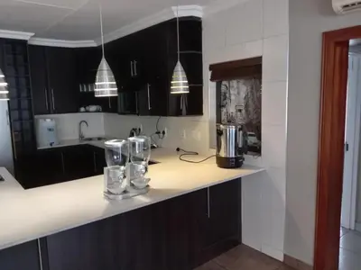 a kitchen with black cabinets and a white counter top at KWR B&B in Witbank