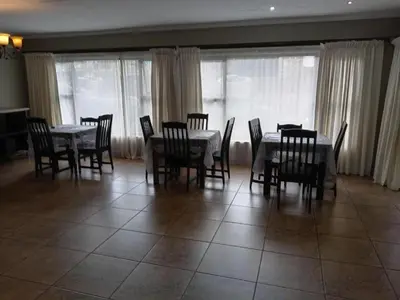 a dining room with tables and chairs and windows at KWR B&B in Witbank
