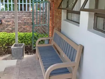 a wooden bench sitting next to a brick building at KWR B&B in Witbank