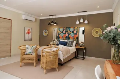 a bedroom with a bed and chairs and a table at Lions View Accommodation in Nelspruit