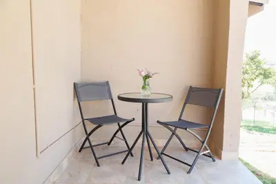 a table with two chairs and a vase of flowers on it at Lions View Accommodation in Nelspruit