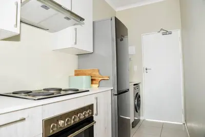 a white kitchen with a stove and a refrigerator at Cozy Hidden gem in Midrand in Midrand