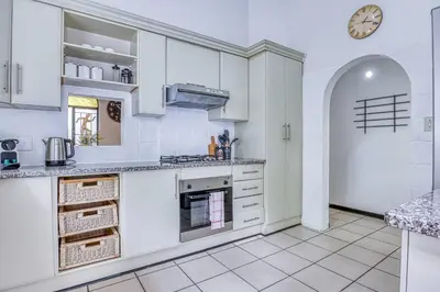 a kitchen with white cabinets and a clock on the wall at Modern Spanish House-3br-pool-solar-samrand in Centurion