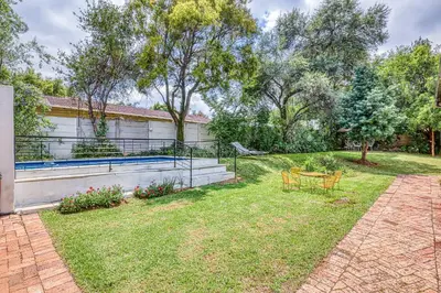 a backyard with a table and chairs and trees at The Cottage-1 Bed-pool-bbq-fibre-solar-samrand in Centurion