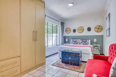 a bedroom with a bed and a red couch at The Cottage-1 Bed-pool-bbq-fibre-solar-samrand in Centurion