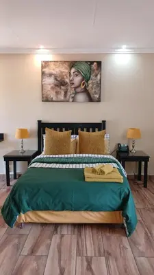 a bedroom with a bed with a painting on the wall at South Gate Lodge in Polokwane