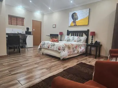 a living room with a bed and a kitchen at South Gate Lodge in Polokwane