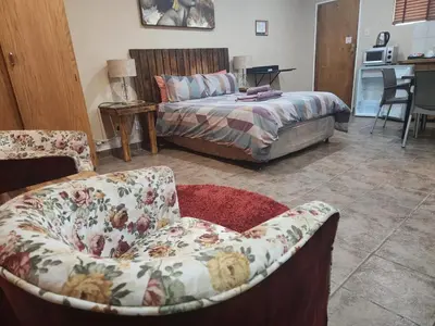 a bedroom with a bed and a couch and a chair at South Gate Lodge in Polokwane