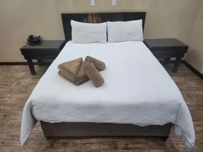 a bed with two towels and two pillows on it at South Gate Lodge in Polokwane