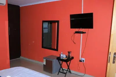 a room with a red wall with a television and a table at ZWIZWO Guest House in Thohoyandou