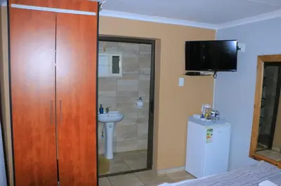 a bathroom with a wooden closet and a sink at ZWIZWO Guest House in Thohoyandou