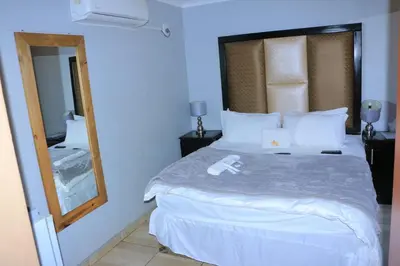 a bedroom with a large bed and a mirror at ZWIZWO Guest House in Thohoyandou