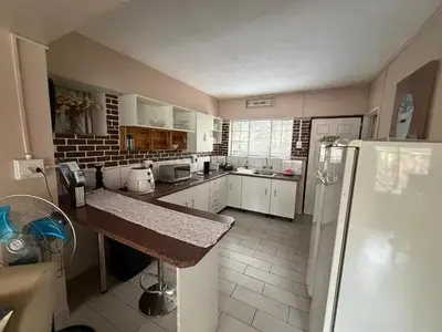 a large kitchen with white cabinets and a refrigerator at Babushka in Marloth Park