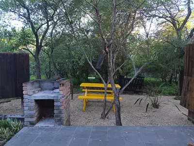 a yellow bench in a park with a brick oven at Babushka in Marloth Park