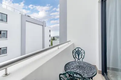 a chair sitting on a balcony looking out at a window at Nosivu@Regency Apartment Hotel in Pretoria