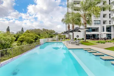 a swimming pool with lounge chairs next to a building at Nosivu@Regency Apartment Hotel in Pretoria