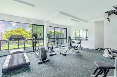 a gym with treadmills and ellipticals in a room with windows at Nosivu@Regency Apartment Hotel in Pretoria