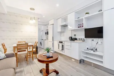 a kitchen and living room with a table and a couch at Nosivu@Regency Apartment Hotel in Pretoria
