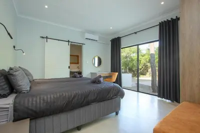 a bedroom with a large bed and a large window at Maroela Safari House in Marloth Park