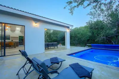 a patio with chairs and a swimming pool at Maroela Safari House in Marloth Park