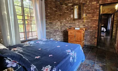a bedroom with a blue bed and a brick wall at Indlovu Inn in Marloth Park