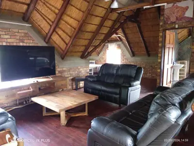 a living room with leather furniture and a flat screen tv at Indlovu Inn in Marloth Park