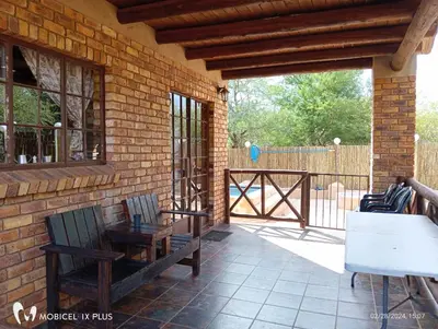 a patio with two chairs and a wooden fence at Indlovu Inn in Marloth Park