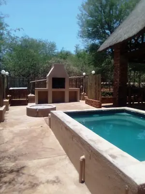 a swimming pool in a yard with a house at Indlovu Inn in Marloth Park