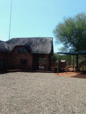 a building with a thatched roof and a pavilion at Indlovu Inn in Marloth Park