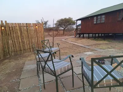 two chairs and a table in a yard at Nyala Bush Cabin in Polokwane
