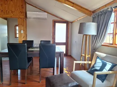 a dining room with a table and chairs and a lamp at Nyala Bush Cabin in Polokwane