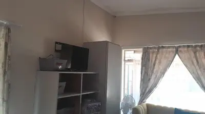a living room with a window and a tv at A humble abode that is cozy in Centurion