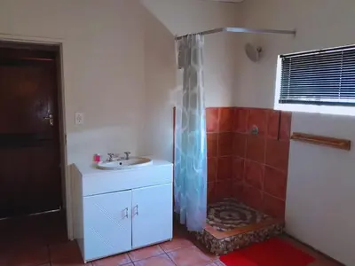 a bathroom with a sink and a shower with a shower curtain at A humble abode that is cozy in Centurion