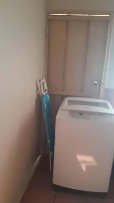 a washer and dryer sitting in a corner of a room at A humble abode that is cozy in Centurion