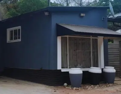 a blue house with three trash cans in front of it at A humble abode that is cozy in Centurion
