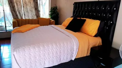 a bedroom with a large bed with orange pillows at A humble abode that is cozy in Centurion