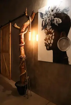 a room with a tree trunk next to a painting at Shongololo Bush Villa in Marloth Park