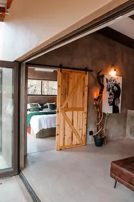 a bedroom with a sliding barn door and a bed at Shongololo Bush Villa in Marloth Park