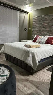 a bedroom with a large bed and a brick wall at Lake Boutique Hotel in Thohoyandou