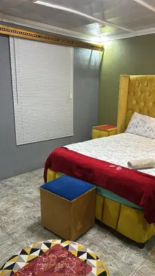 a bedroom with a bed and a ottoman next to it at Lake Boutique Hotel in Thohoyandou