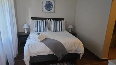 a bedroom with a bed with white sheets and pillows at Grobler's Haven in Pretoria