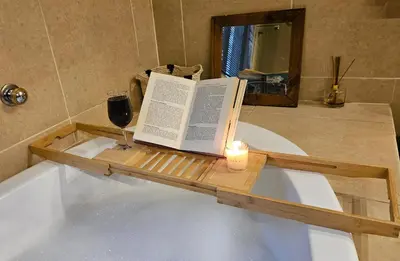 a candle and a book on a bath tub with a glass of wine at Grobler's Haven in Pretoria