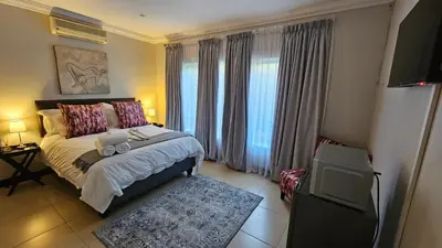 a bedroom with a bed and a tv in it at Grobler's Haven in Pretoria